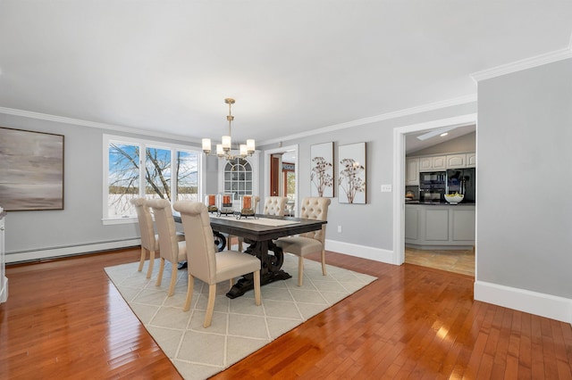 dining space with baseboard heating, light hardwood / wood-style floors, ornamental molding, a notable chandelier, and vaulted ceiling