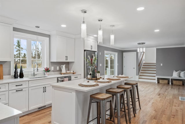 kitchen with a center island, decorative light fixtures, white cabinetry, stainless steel appliances, and sink