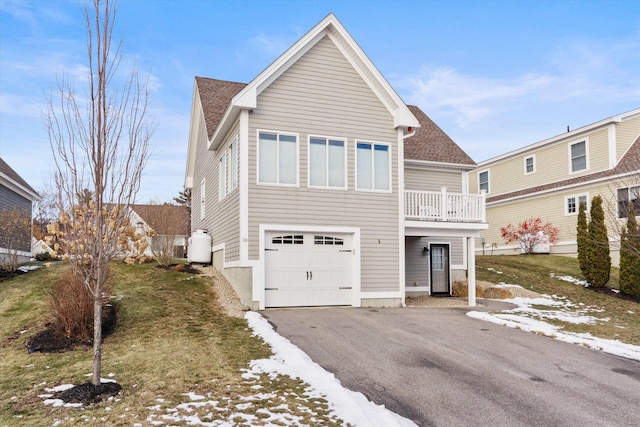 view of property with a balcony, a front lawn, and a garage