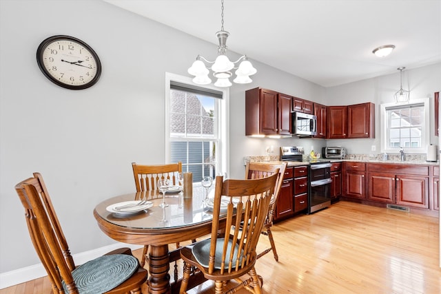 dining area featuring sink, an inviting chandelier, and light hardwood / wood-style flooring