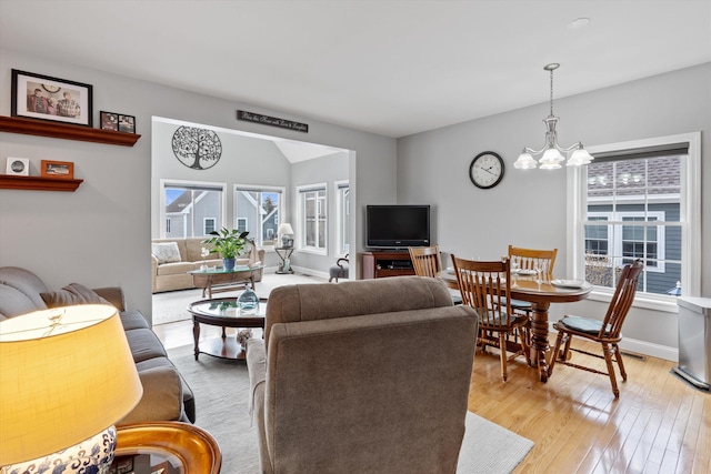 living room with light wood-type flooring, a healthy amount of sunlight, and a notable chandelier