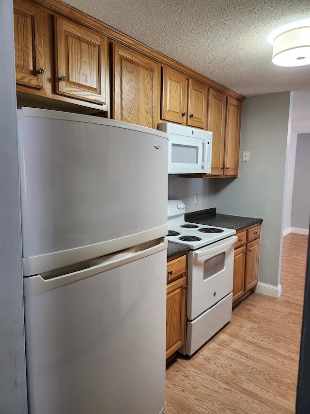 kitchen with white appliances, a textured ceiling, and light hardwood / wood-style flooring