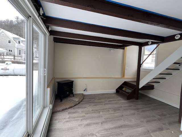 interior space with a wood stove, beam ceiling, and light hardwood / wood-style flooring