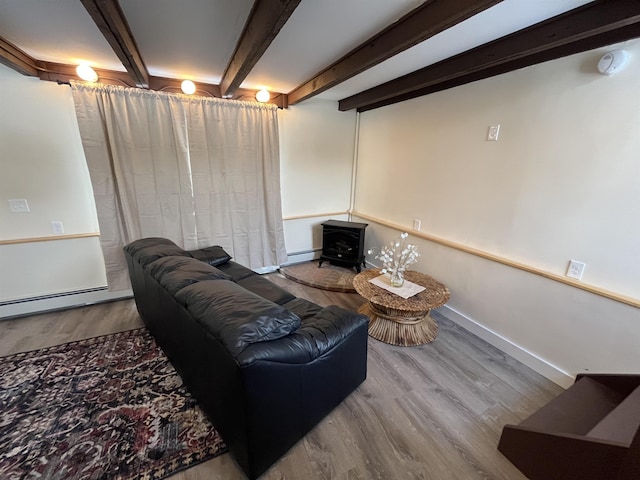 living room with a baseboard heating unit, beamed ceiling, a wood stove, and hardwood / wood-style floors