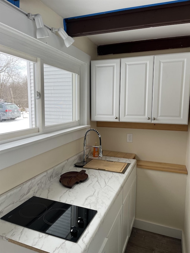 kitchen with black electric stovetop, white cabinets, and sink