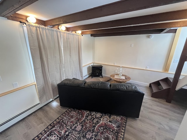 living room with hardwood / wood-style flooring, a wood stove, baseboard heating, and beam ceiling