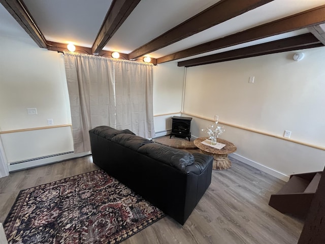 living room featuring a baseboard heating unit, beamed ceiling, a wood stove, and hardwood / wood-style flooring