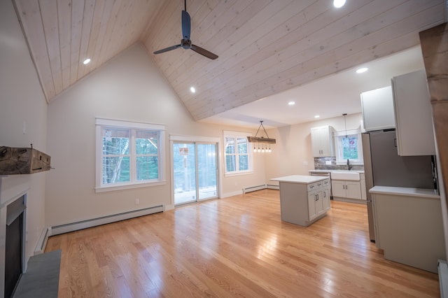 kitchen with a kitchen island, pendant lighting, white cabinetry, a baseboard heating unit, and light hardwood / wood-style floors