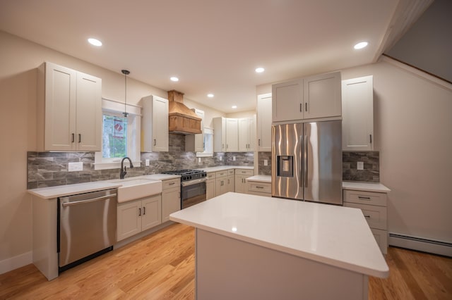 kitchen with sink, hanging light fixtures, stainless steel appliances, custom range hood, and a kitchen island