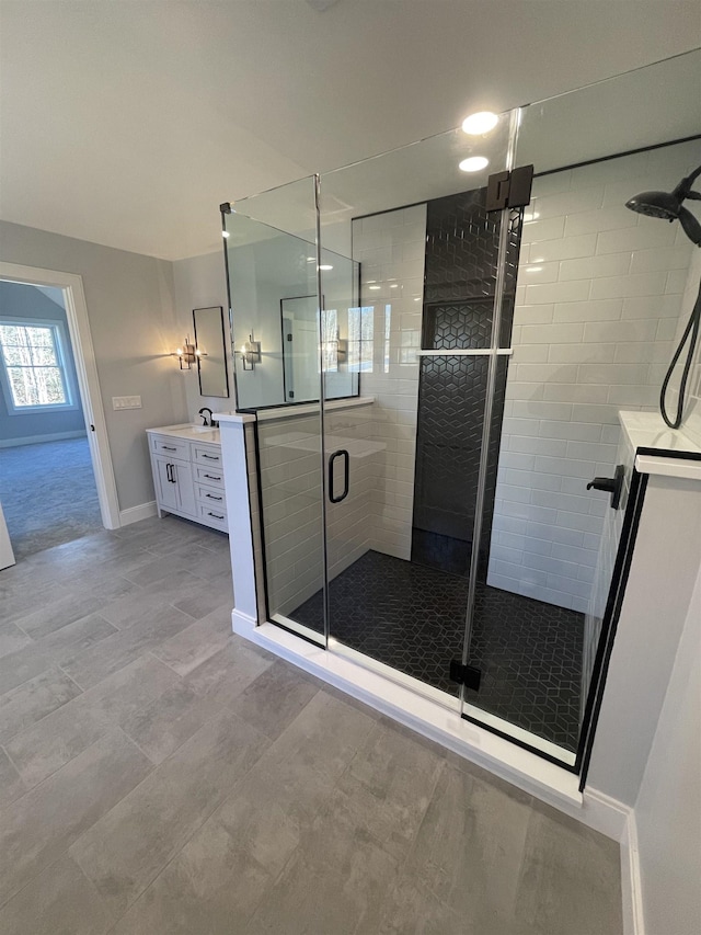 bathroom featuring a shower with shower door and vanity