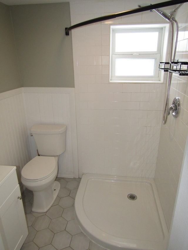 bathroom featuring vanity, toilet, tile patterned flooring, and tiled shower