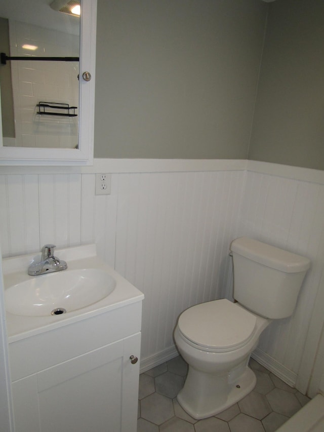 bathroom with toilet, vanity, and tile patterned flooring