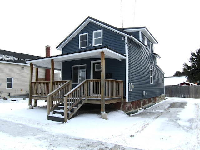 snow covered rear of property with a porch