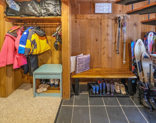 mudroom with dark carpet and wood walls