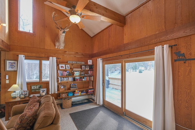 interior space featuring carpet floors, wood walls, ceiling fan, and a healthy amount of sunlight