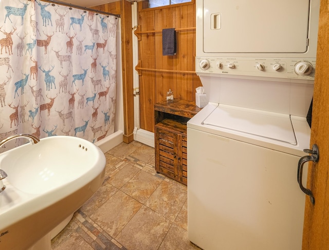 laundry room featuring stacked washing maching and dryer and wooden walls