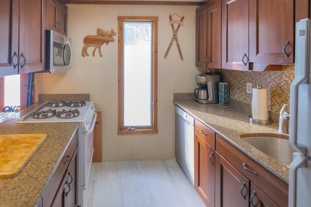 kitchen featuring backsplash, a wealth of natural light, light stone counters, and stainless steel appliances