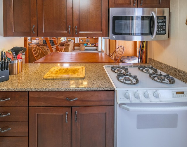 kitchen featuring white gas stove and light stone counters