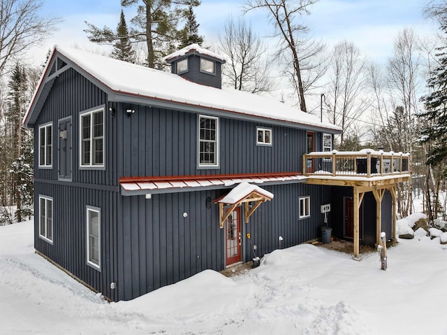 snow covered rear of property featuring board and batten siding and a wooden deck