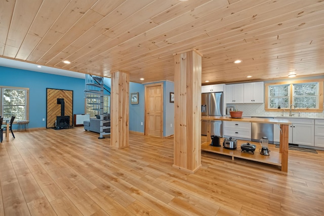 living room with wooden ceiling, light wood-type flooring, a wood stove, and recessed lighting