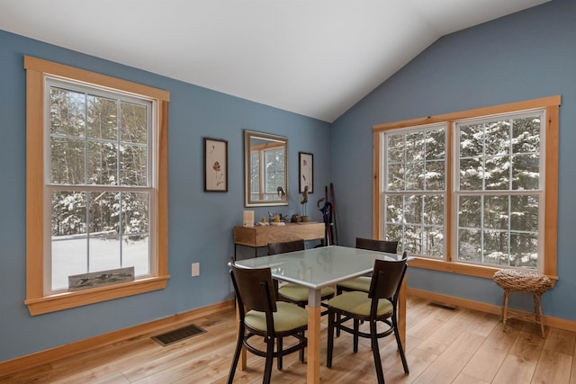 dining room with vaulted ceiling, light wood finished floors, and visible vents