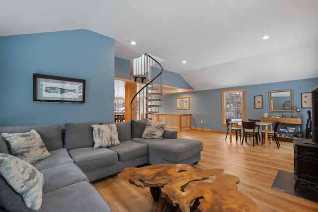 living area with lofted ceiling, baseboards, stairs, light wood-style floors, and a wood stove