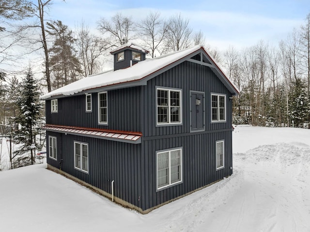 snow covered property featuring metal roof and board and batten siding