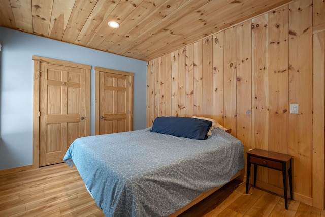 bedroom featuring wooden ceiling, wooden walls, baseboards, and wood finished floors