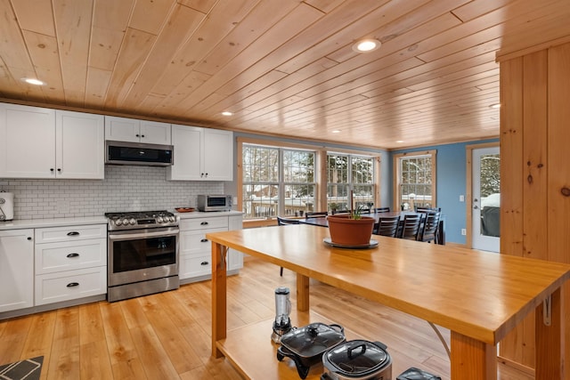 kitchen featuring stainless steel appliances, white cabinets, light countertops, decorative backsplash, and light wood finished floors