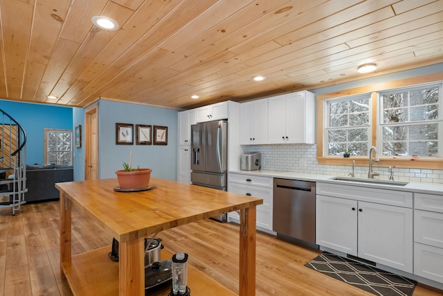 kitchen with light wood finished floors, appliances with stainless steel finishes, a sink, and decorative backsplash