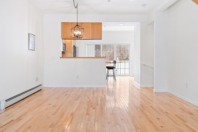 interior space featuring baseboard heating, a notable chandelier, and light hardwood / wood-style floors