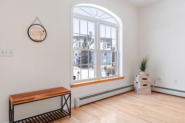 living area featuring baseboard heating and light hardwood / wood-style flooring