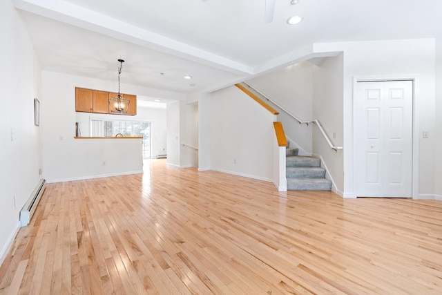 unfurnished living room featuring light wood-type flooring, baseboard heating, and a notable chandelier