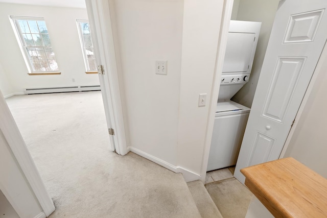 laundry area featuring light carpet, stacked washer / drying machine, and a baseboard radiator