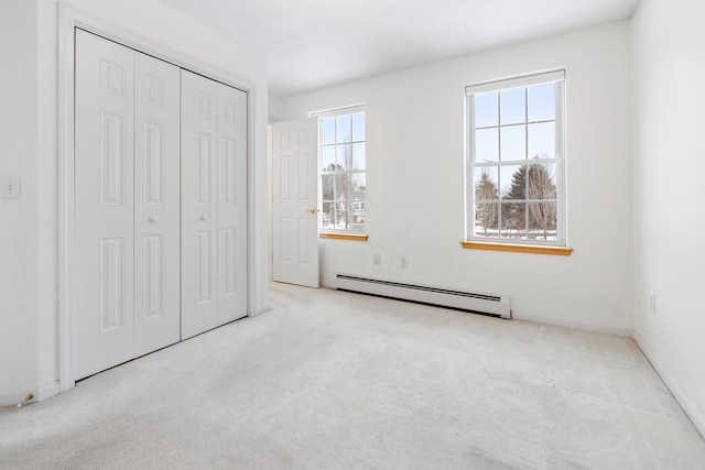 unfurnished bedroom featuring light colored carpet, a closet, multiple windows, and a baseboard radiator