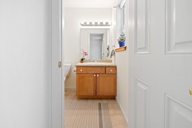 bathroom with toilet, vanity, and tile patterned floors