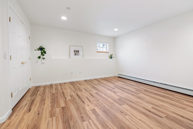 spare room featuring a baseboard heating unit and light hardwood / wood-style flooring