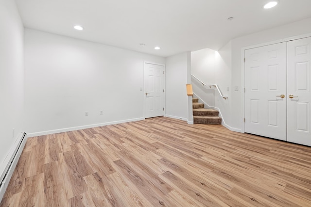 unfurnished room featuring baseboard heating and light hardwood / wood-style floors