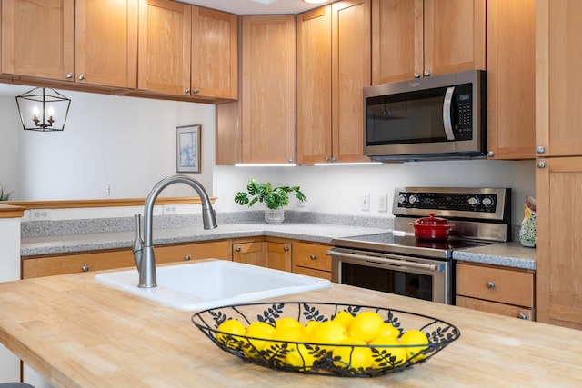 kitchen with sink, wood counters, an inviting chandelier, and stainless steel appliances