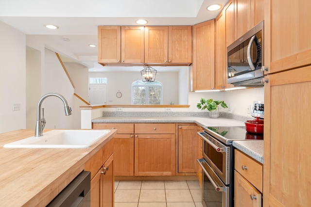 kitchen featuring sink, light tile patterned floors, stainless steel appliances, and an inviting chandelier