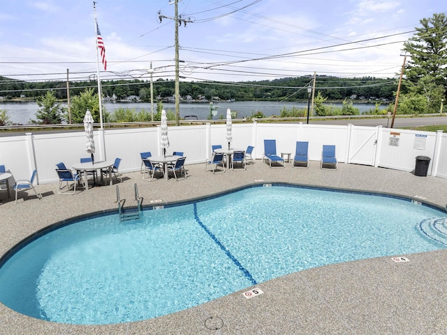 view of swimming pool with a water view and a patio