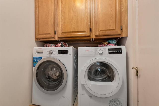 clothes washing area featuring washing machine and dryer and cabinets