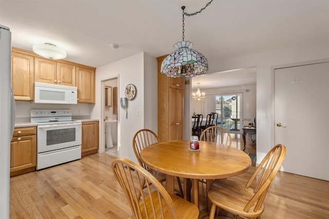 dining space with light hardwood / wood-style floors and an inviting chandelier