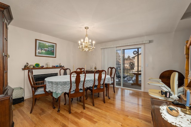 dining area with light hardwood / wood-style floors and a notable chandelier