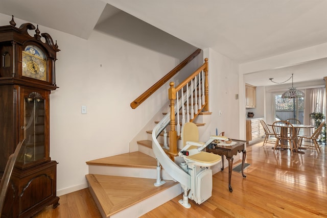 stairway with wood-type flooring and a notable chandelier