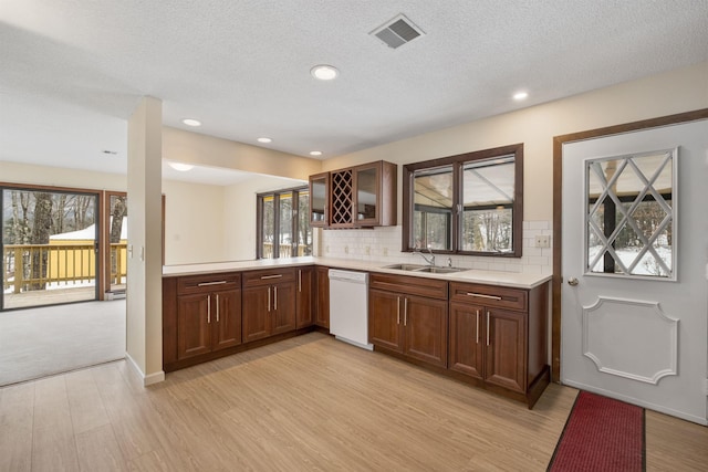 kitchen featuring dishwasher, decorative backsplash, sink, light hardwood / wood-style flooring, and a textured ceiling