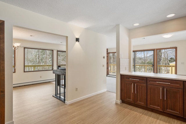 kitchen featuring a baseboard heating unit, decorative backsplash, a notable chandelier, a textured ceiling, and light hardwood / wood-style flooring