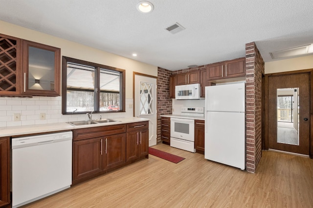 kitchen featuring sink, light hardwood / wood-style floors, plenty of natural light, and white appliances