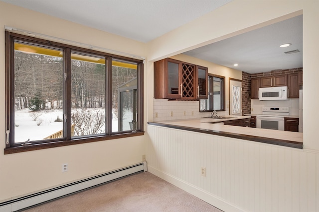 kitchen with light carpet, kitchen peninsula, white appliances, baseboard heating, and sink