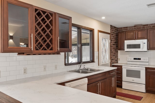 kitchen featuring backsplash, white appliances, light wood-type flooring, light stone counters, and sink